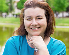 Happy cheerful woman enjoying weekend and leisure time outdoors. Middle aged Caucasian lady in casual standing in park near pond and smiling at camera. Outdoor female portrait concept